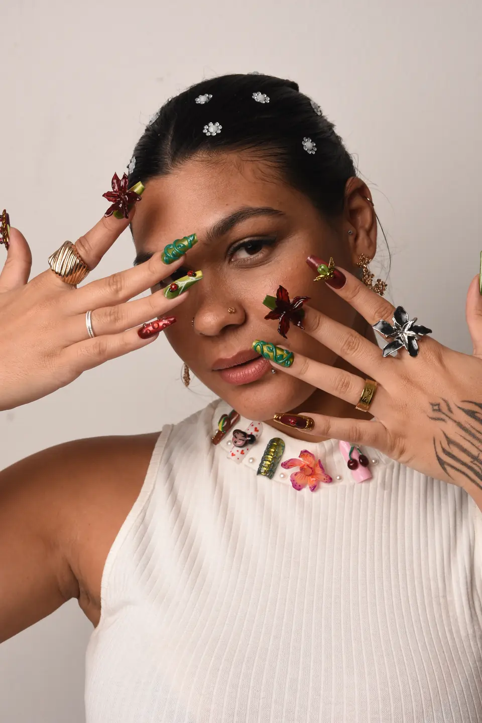 Beatriz Concept com as duas mãos diante do rosto, mostrando unhas longas decoradas em 3D com flores e folhas