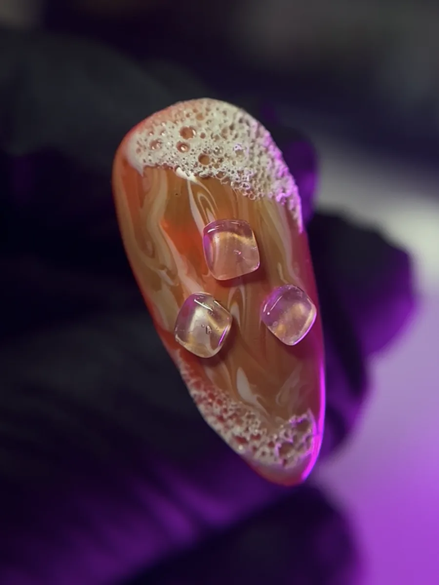 Unha da Beatriz Concept com gel esfumado em laranja e rosa, bolhas em relevo e três pedras de gel transparentes